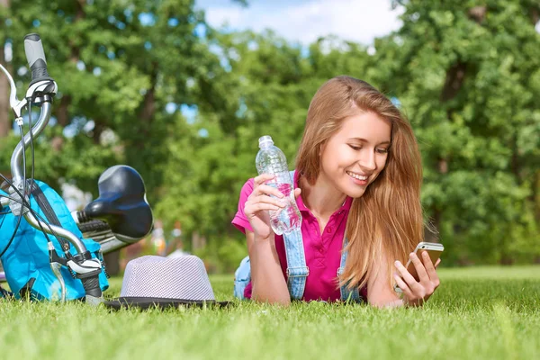 Wanita muda menggunakan ponsel pintarnya di taman — Stok Foto