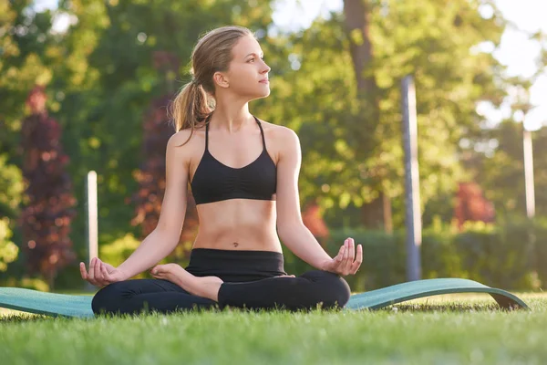 Giovane donna che pratica yoga all'aperto al parco — Foto Stock