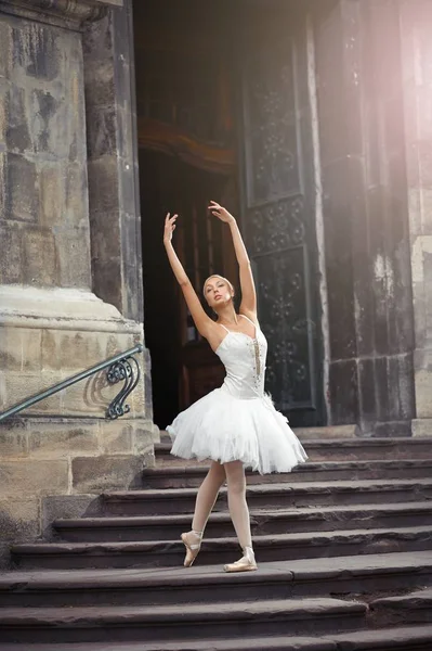 Beautiful ballerina dancing near an old building