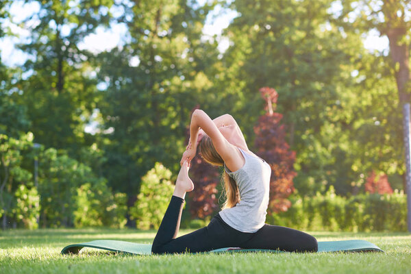 Young woman practicing yoga outdoors at the park