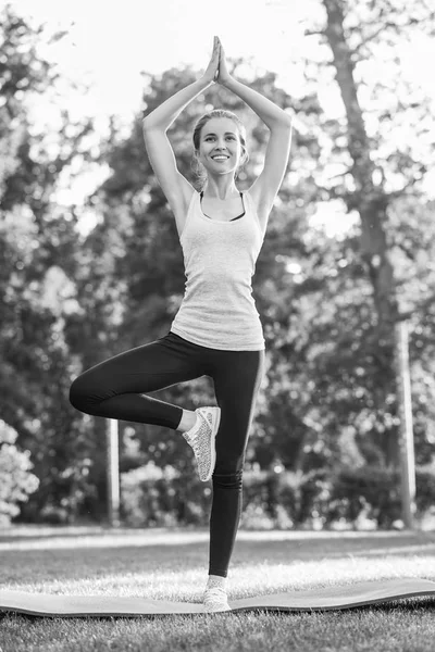 Jeune femme pratiquant le yoga en plein air au parc — Photo