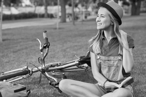 Junge Frau liest nach Fahrradtour im Stadtpark ein Buch — Stockfoto