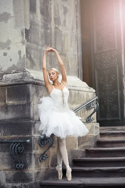 Beautiful ballerina dancing near an old building