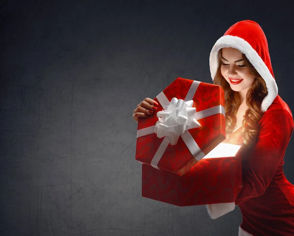 Snow Maiden in red suit smiling holding a gift, opens a gift on