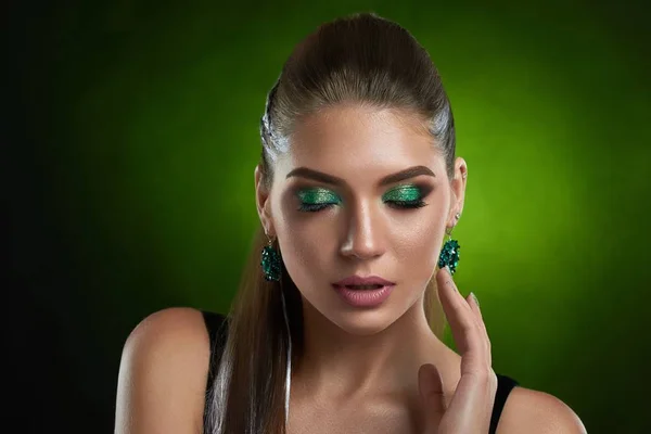 Chica morena sensual con maquillaje verde tocando la piel de bronce de la cara . — Foto de Stock