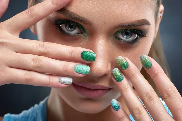 Mulher morena com manicure brilhante e maquiagem verde mostrando unhas . — Fotografia de Stock