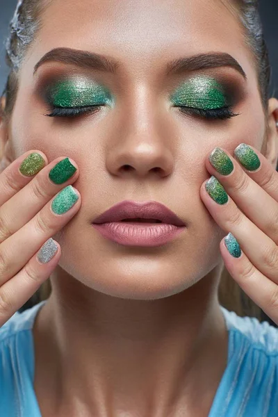 Femme à la peau bronze, manucure brillante et maquillage aux couleurs vertes . — Photo