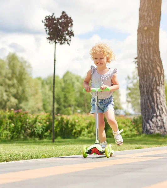 Kleines Mädchen auf einem Motorroller im Park — Stockfoto