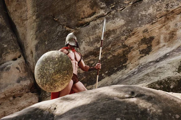 Greek warrior posing on rocks — Stock Photo, Image