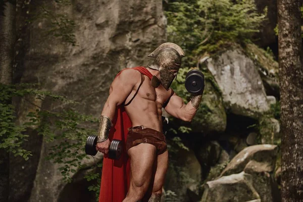Atletisk gladiator poserar med hantlar — Stockfoto