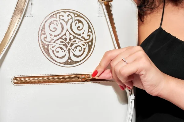Μια partmodel φέρνει μια άσπρη τσάντα με χρυσές μοτίβο — Φωτογραφία Αρχείου