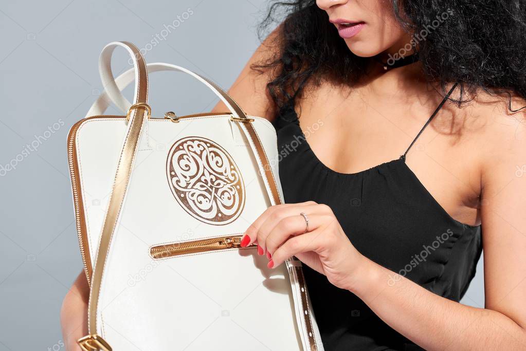 A partmodel carries a white bag with a golden pattern