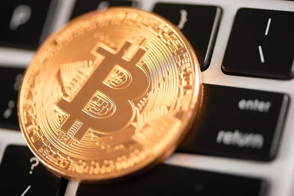 Närbild av gyllene bitcoin som huvudsakliga virtuell valuta placeras på laptop tangentbord. — Stockfoto