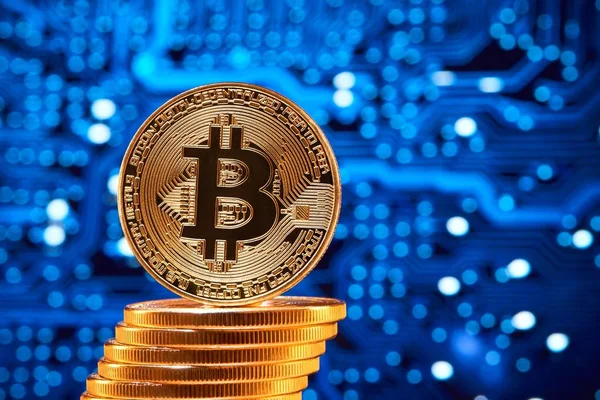Stack of golden bitcoins with one bitcoin on its edge placed on blurred blue circuit — Stock Photo, Image