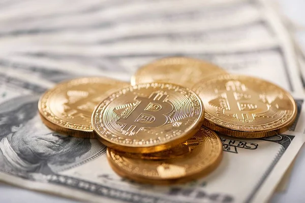 Stack av gyllene krypterade bitcoins liggande på dollar sedlar presenterar nya futuristiska digital valuta. — Stockfoto