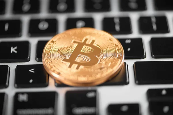 En gyllene bitcoin som världen största kryptovaluta placeras på laptop tangentbord — Stockfoto