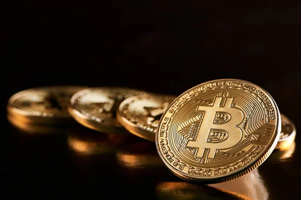 One golden bitcoin as main cryptocurrency in front of other golden bitcoins isolated on balck background — Stock Photo, Image