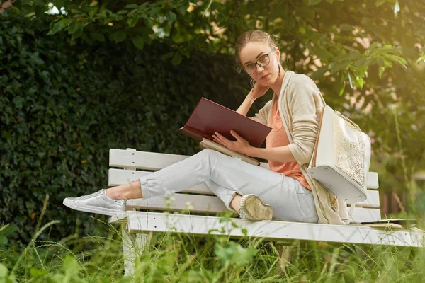 Foto de una chica de moda leyendo en el banco del parque — Foto de Stock
