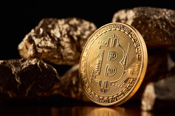 Shiny golden bitcoin being biggest cryptocurrency worldwide together with lumps of gold on black background — Stock Photo, Image