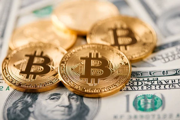 Närbild av bitcoin största världsomspännande kryptovaluta liggande på bakgrund av hundra dollar sedlar — Stockfoto