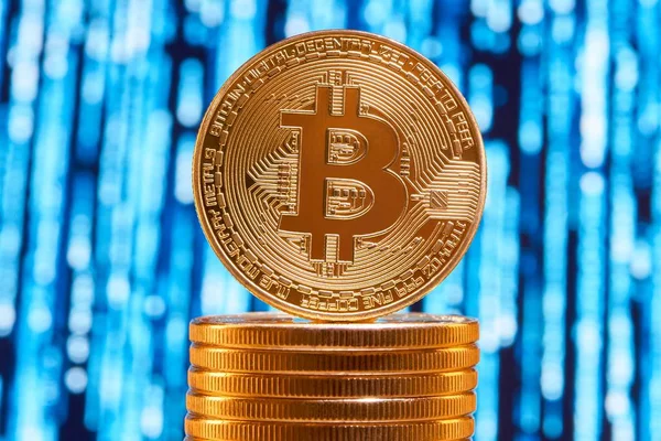 One bitcoin on edge placed on stack of golden bitcoins with blurred blue circuit on background — Stock Photo, Image