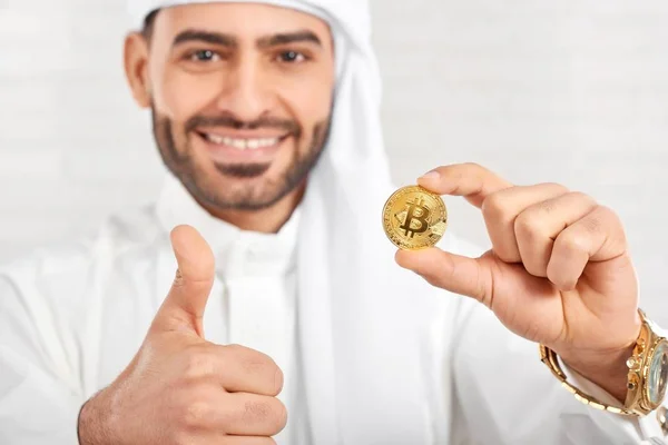 Закри мусульманських усміхнений чоловік тримає bitcoin на білому тлі. — стокове фото