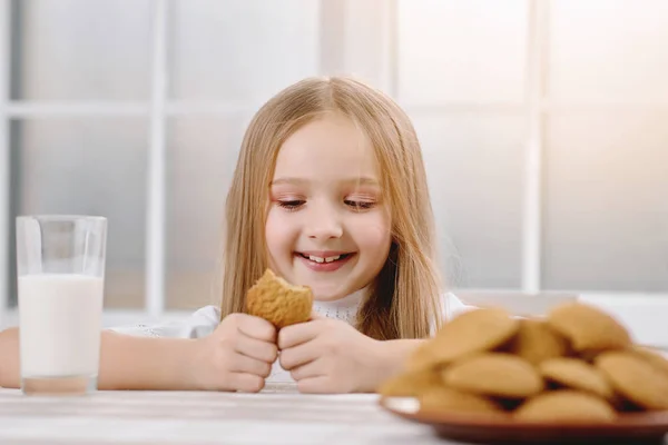 Маленькая симпатичная девочка улыбается во время еды сладкое печенье . — стоковое фото
