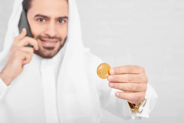 Golden bitcoin hold by handsome smiling Muslim male — Stock Photo, Image