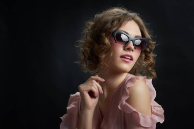 Kıvırcık kız moda güneş gözlüğü takıyor.