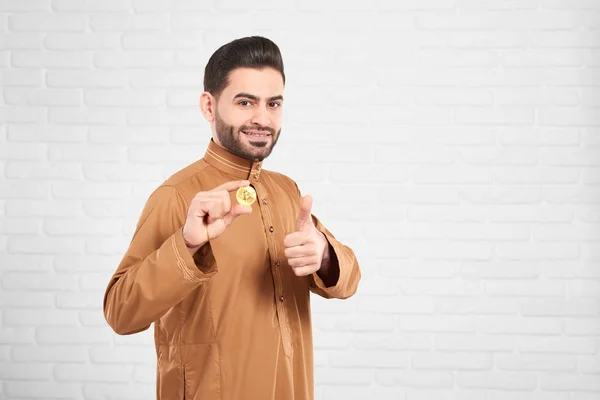 Młody atrakcyjny muzułmańskich model mężczyzna bycie szczęśliwym, prezentując złote bitcoin i kciuki up — Zdjęcie stockowe