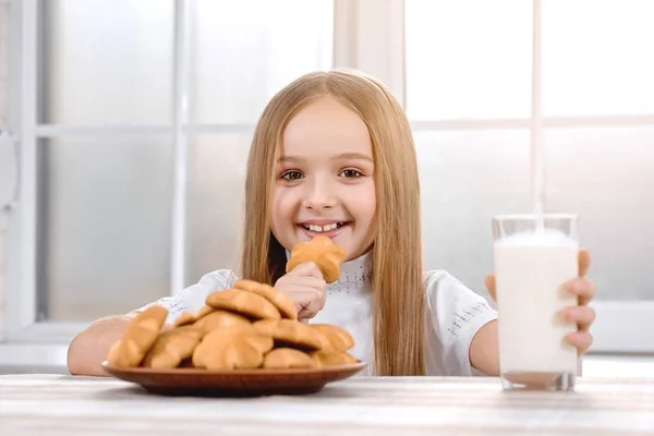 Милая маленькая девочка ест печенье с молоком и улыбается — стоковое фото