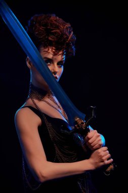 Büyük çelik kılıç tutarak tehlikeli savaşçı kadını.