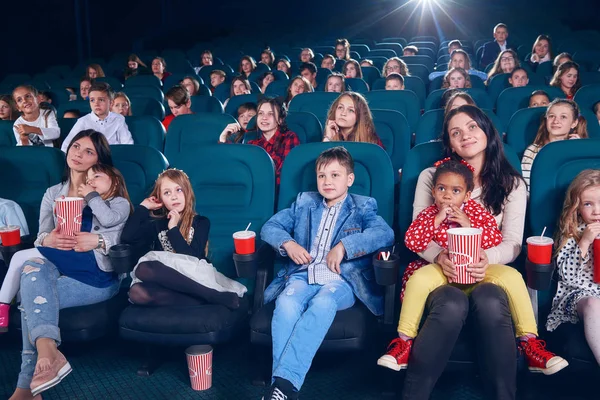 Mother watching movie with little children on first cinema row.