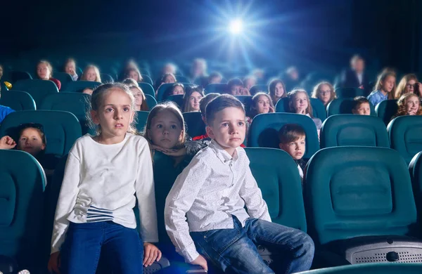 Front tview of little boy and girl sitting in the cinema hall . — стоковое фото