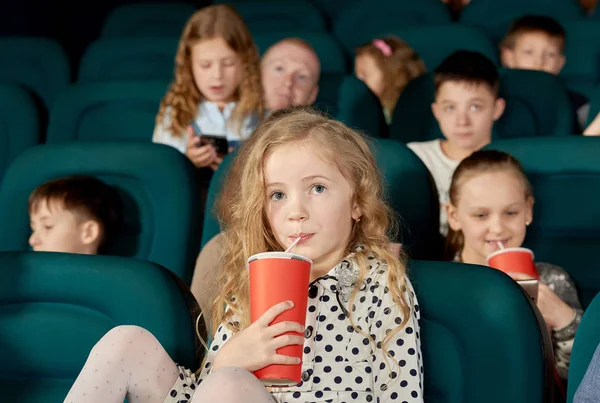 Όμορφο κορίτσι με ξανθά μαλλιά πόσιμο cola στον κινηματογράφο. — Φωτογραφία Αρχείου