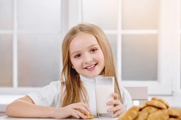 Sorrindo menina bebe leite com biscoitos . — Fotografia de Stock