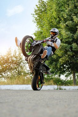 Male biker practicing stunts on a bike. clipart