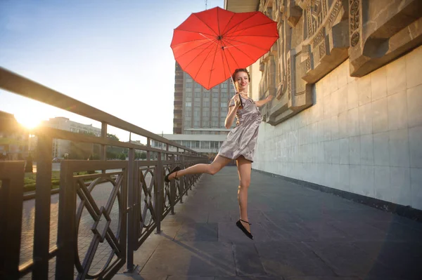 Dansande flicka innehav hjärtformade röda paraply. — Stockfoto