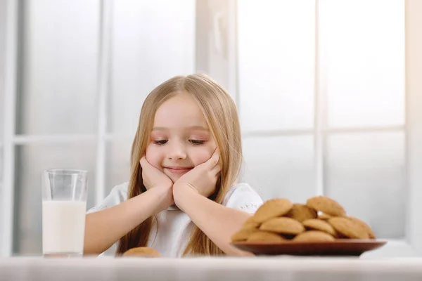 Прекрасная маленькая девочка с светлыми волосами сидит рядом с печеньем . — стоковое фото
