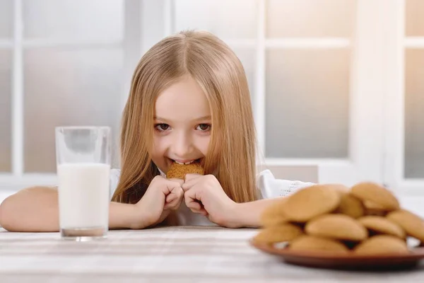 Милая маленькая девочка с светлыми волосами сидит рядом с печеньем . — стоковое фото