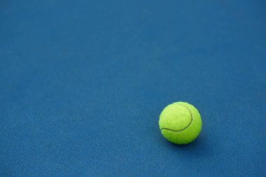 Yellow tennis ball on blue carpet. clipart