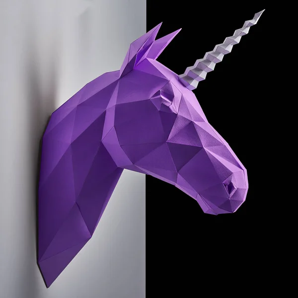 Bright violet coloured unicorn hanging on the contrast white and black wall.