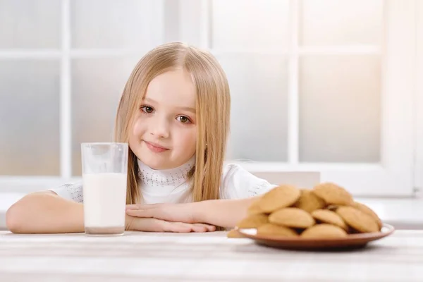 A garota mais fofa com cabelo loiro se senta perto de biscoitos . — Fotografia de Stock