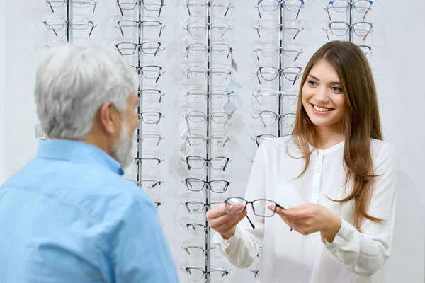Selig lächelnder Assistent zeigt alten Mann die Brille. — Stockfoto