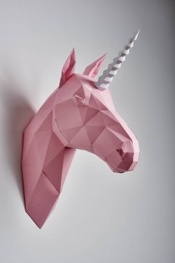 Beyaz duvarda asılı pembe renkli tek boynuzlu at.