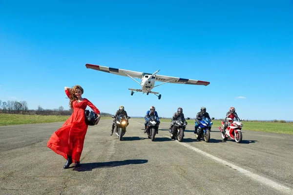 흰색 비행기는 오토바이 여자 wering 빨간 드레스에 자전거 비행. — 스톡 사진
