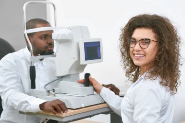 Dost gülümseyen doktor hastaların görme denetliyor.