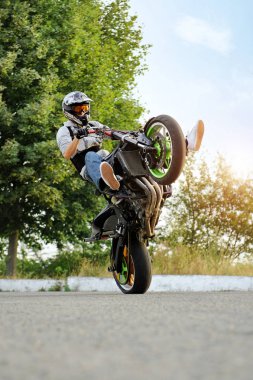 Sideview of biker riding motorcycle in extreme way. clipart