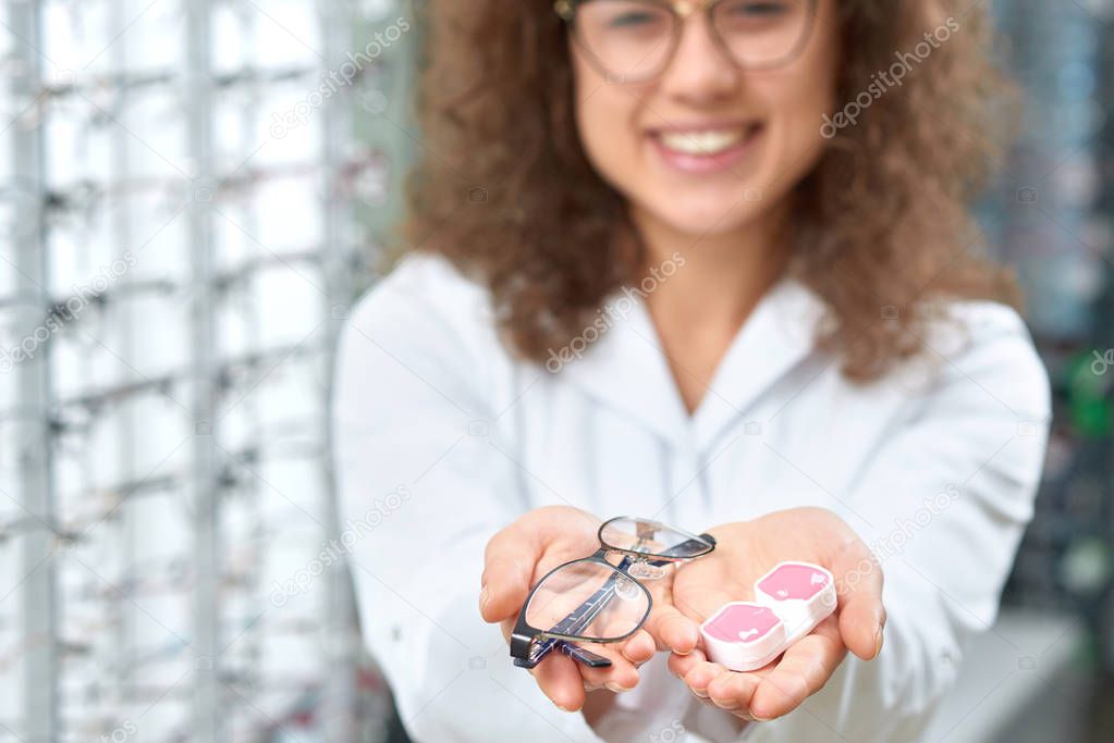 Blurred photo of smiling oculist helping to choose glasses.