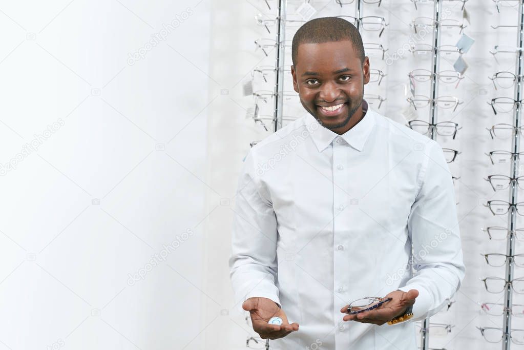Frontview of smiling man trying to choose eyeglasses in optical shop.
